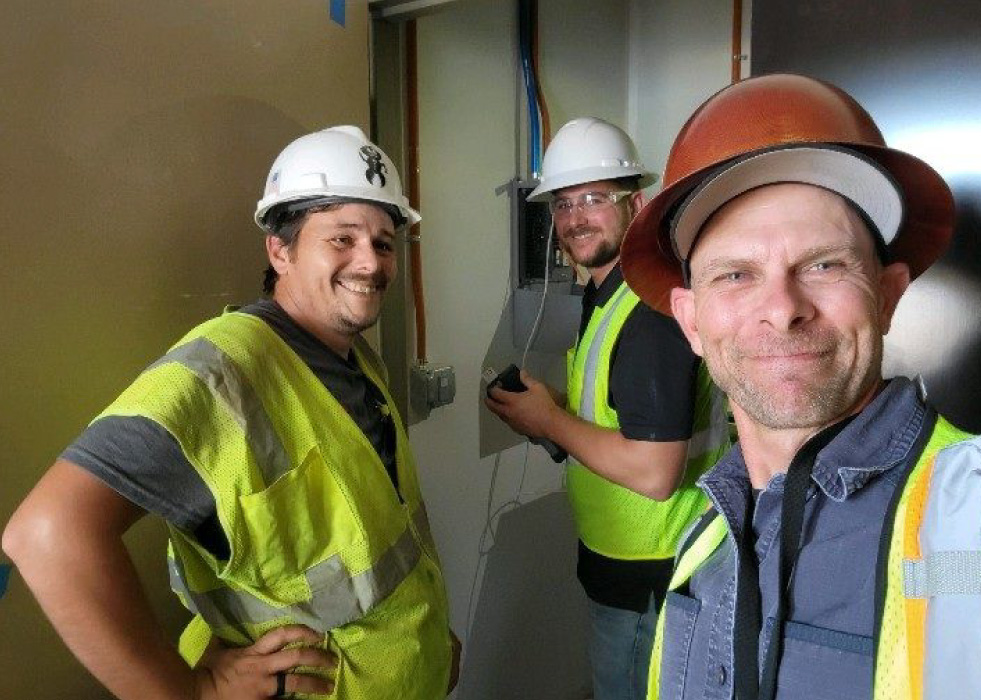 Three Albireo Energy workers wearing hardhats in an office.